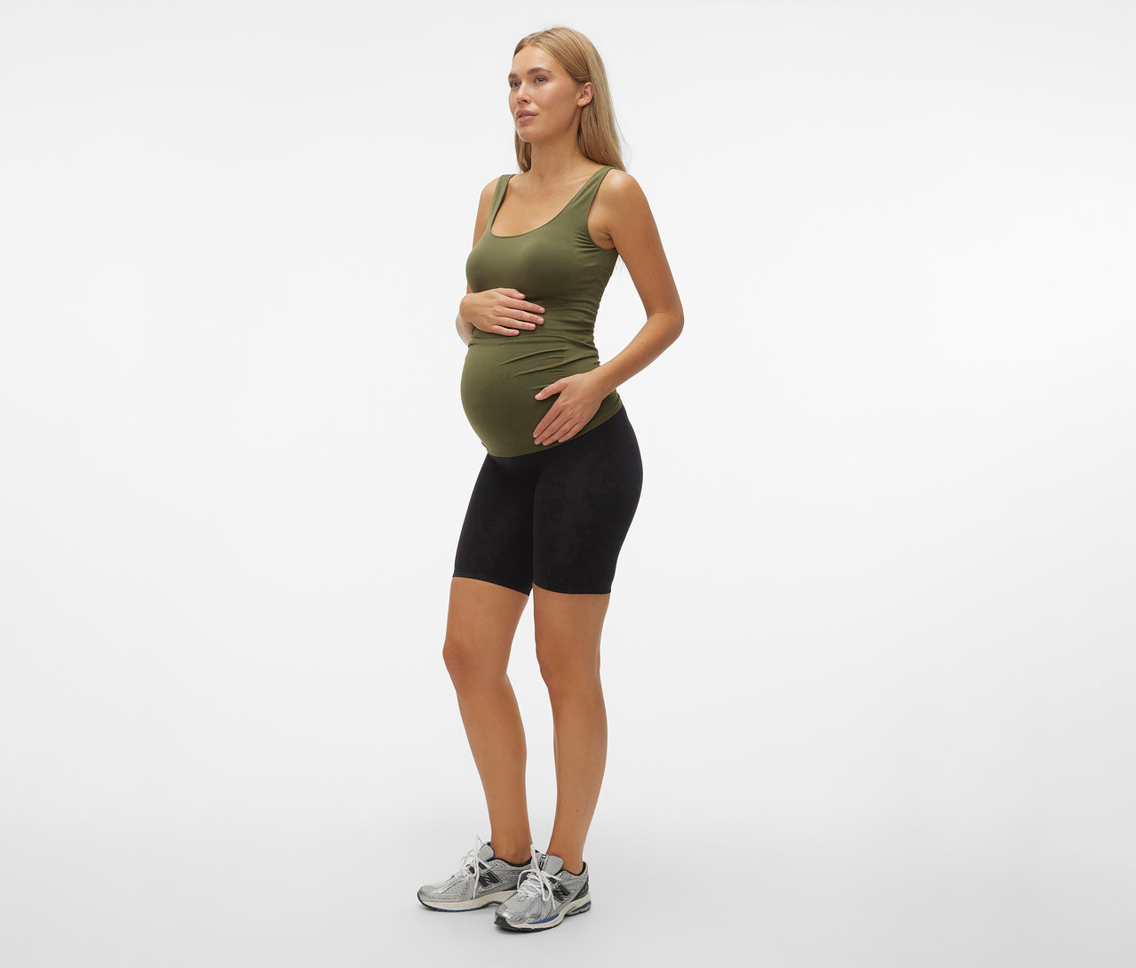 Femme enceinte portant un débardeur vert olive et un Skinny Shorts MAMALICIOUS «
MLTIA JEANNE
», mellow buff noir, debout de profil.