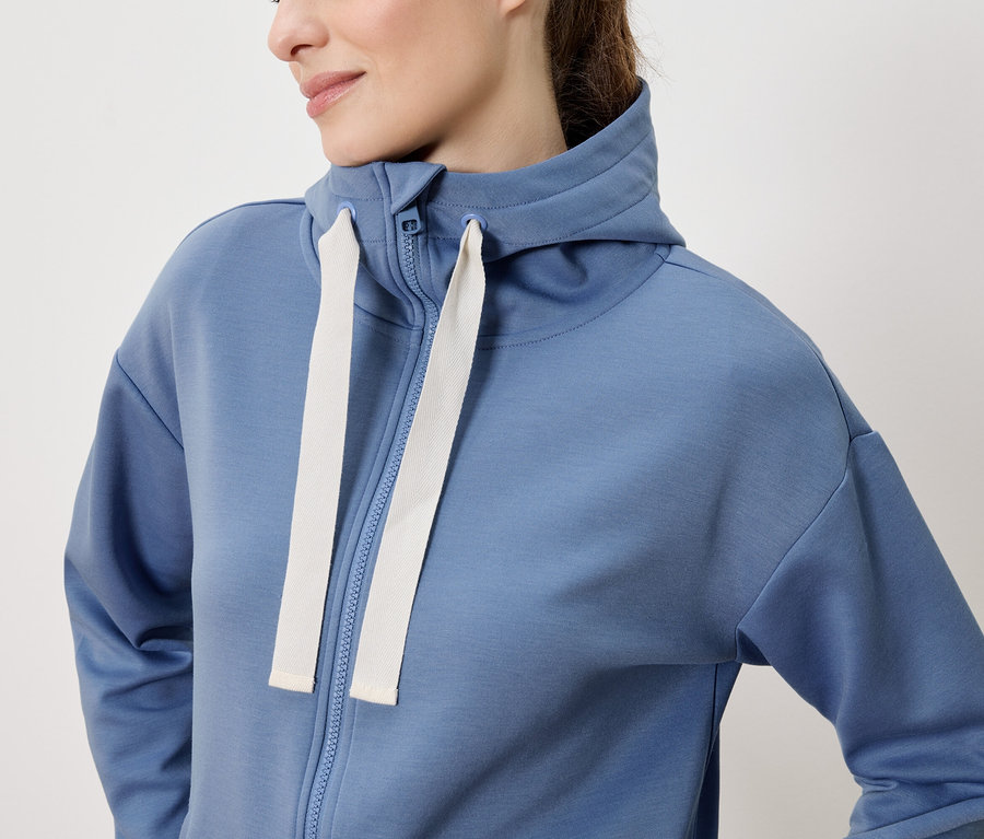 Femme portant un sweat à capuche bleu zippé.