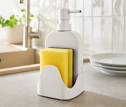 Sur un comptoir de cuisine, un distributeur de savon avec une éponge jaune.