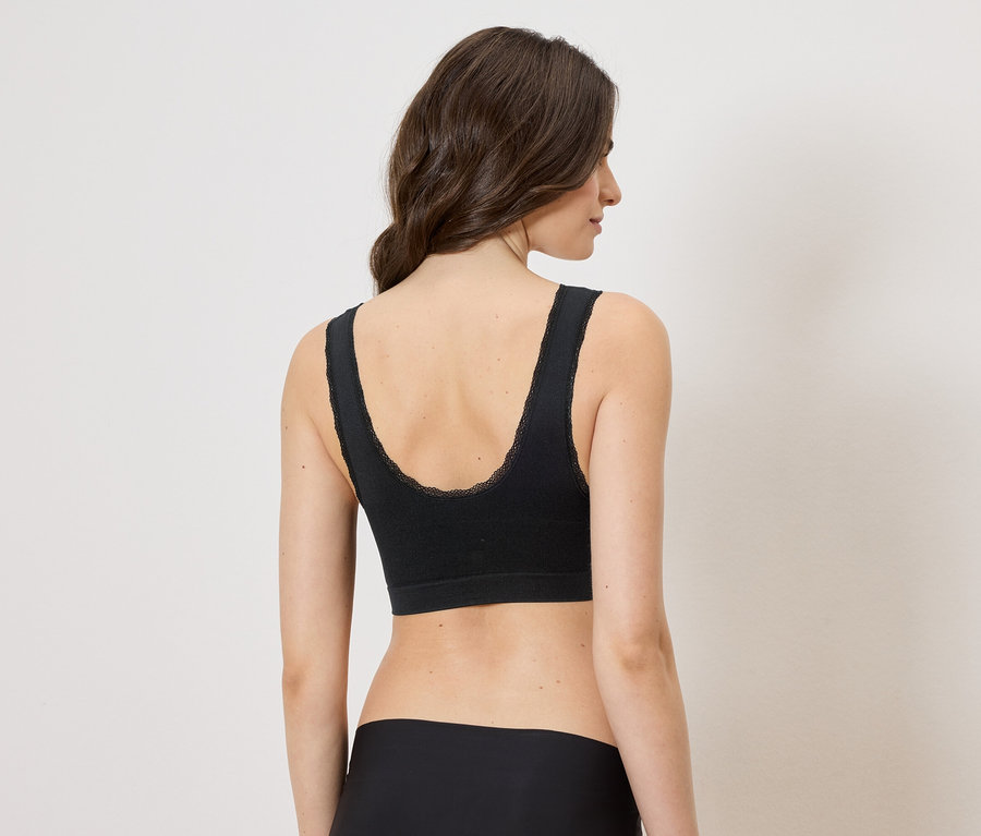 Vue arrière d'une femme aux cheveux bruns portant un soutien-gorge noir avec des finitions en dentelle et une culotte noire.
