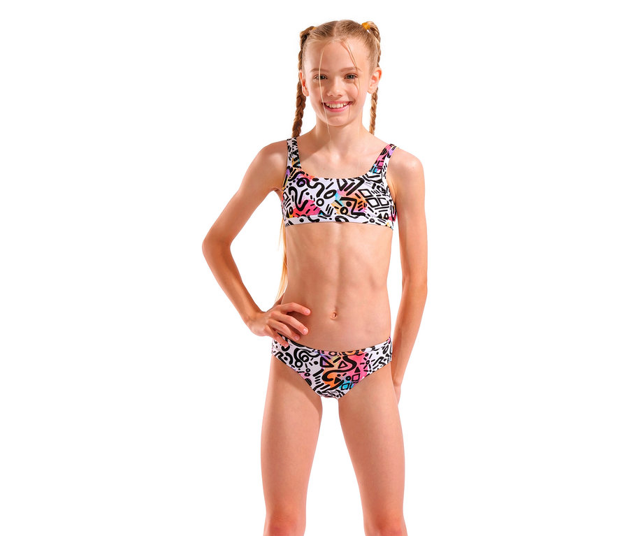 Fille avec des tresses blondes, portant un bikini blanc avec des motifs géométriques, posant avec une main sur la hanche.