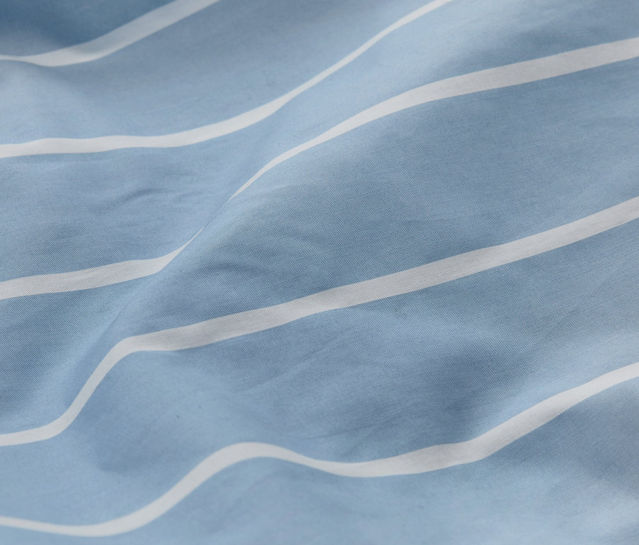 Gros plan d'un tissu bleu clair à rayures blanches avec des plis.