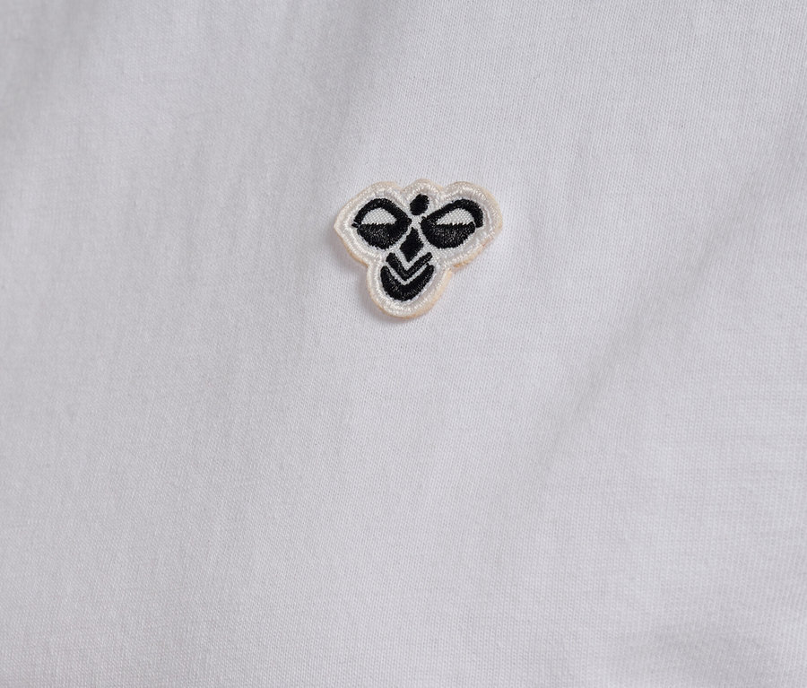 Gros plan sur un t-shirt hummel® pour femme blanc avec un petit logo brodé.