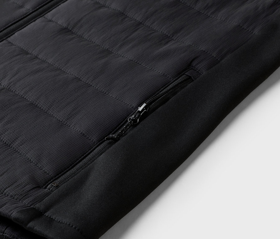 Gros plan sur une veste matelassée noire avec une poche zippée sur la manche.
