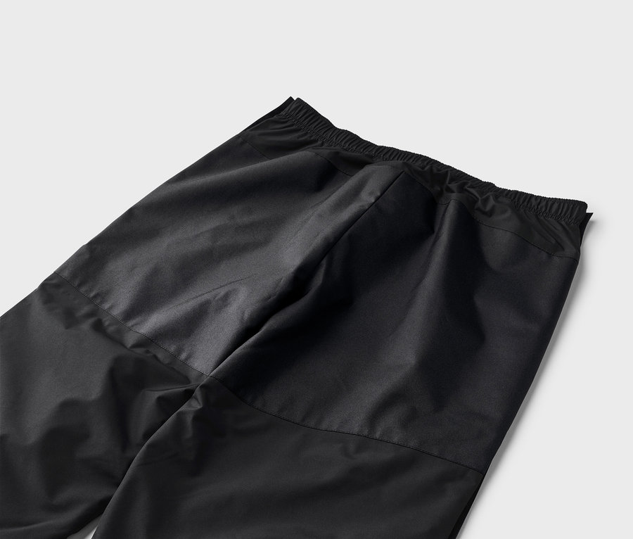 Gros plan d'un pantalon de survêtement noir avec une taille élastique sur fond blanc.