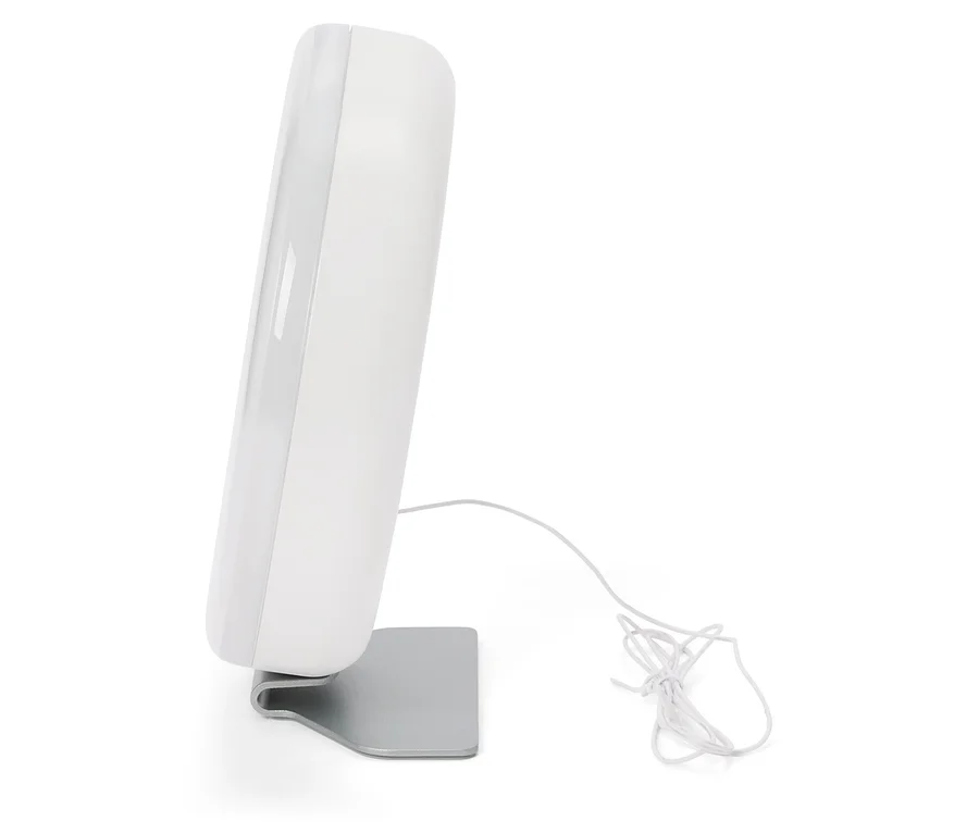 Lampe de luminothérapie blanche posée sur un support argenté, le câble est à côté.