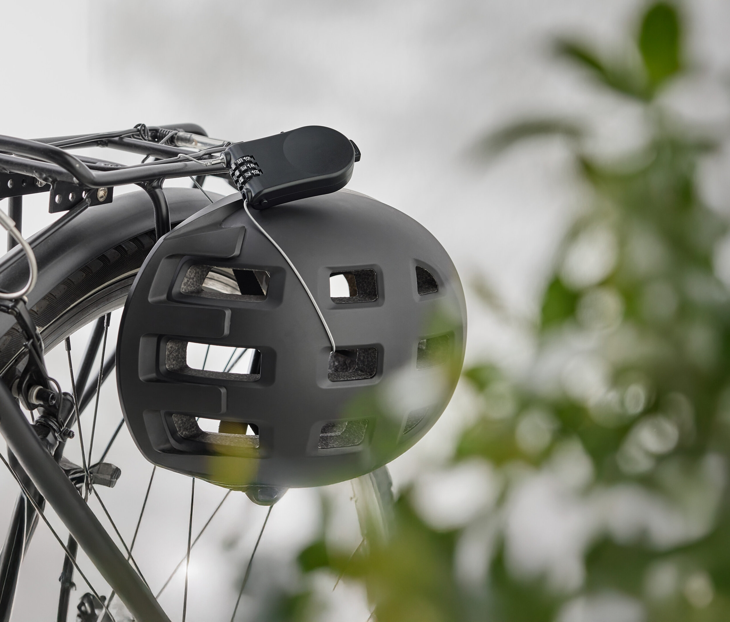 Un casque de vélo noir est suspendu à un porte-bagages de vélo avec un cadenas à combinaison.