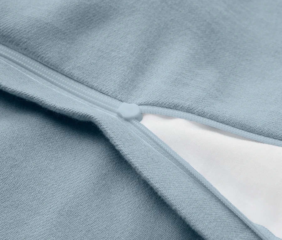 Gros plan sur un tissu bleu clair avec une fermeture éclair partiellement ouverte, révélant un tissu blanc en dessous.