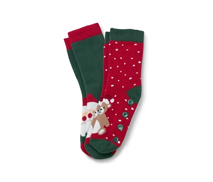 Deux paires de chaussettes de Noël. Une paire est verte avec une bordure rouge et une image du Père Noël et d'un ours en peluche. L'autre paire est rouge avec des points blancs et une bordure et des boutons verts.