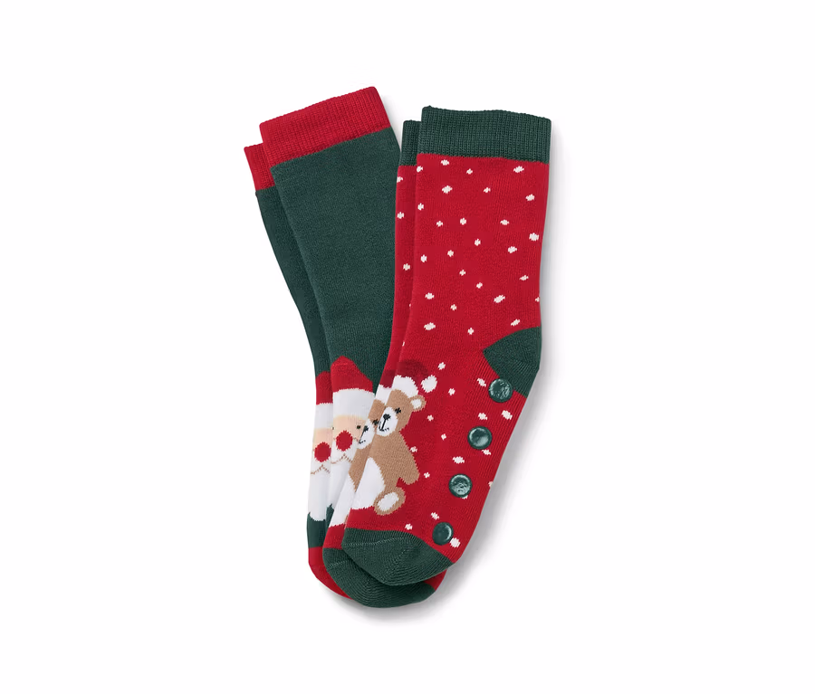 Deux paires de chaussettes de Noël. Une paire est verte avec une bordure rouge et une image du Père Noël et d'un ours en peluche. L'autre paire est rouge avec des points blancs et une bordure et des boutons verts.