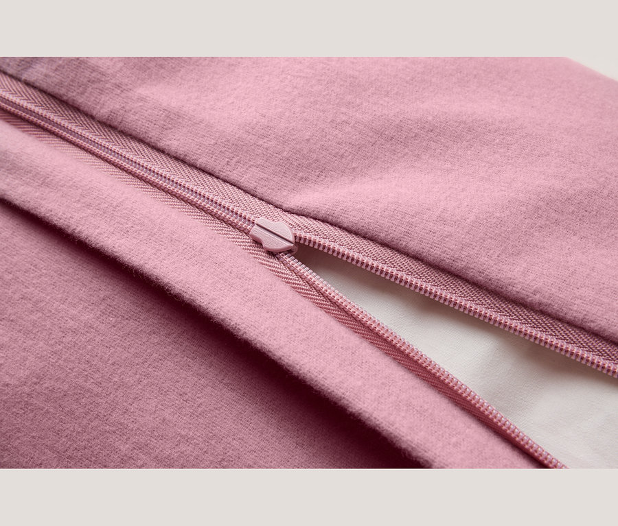 Gros plan d'un tissu rose avec une fermeture éclair rose partiellement ouverte, révélant une doublure blanche en dessous.