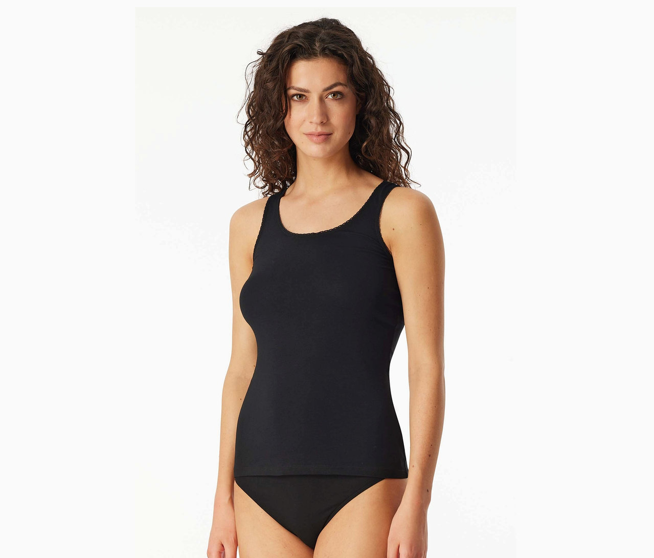 Une femme aux cheveux ondulés porte un débardeur noir et une culotte noire.