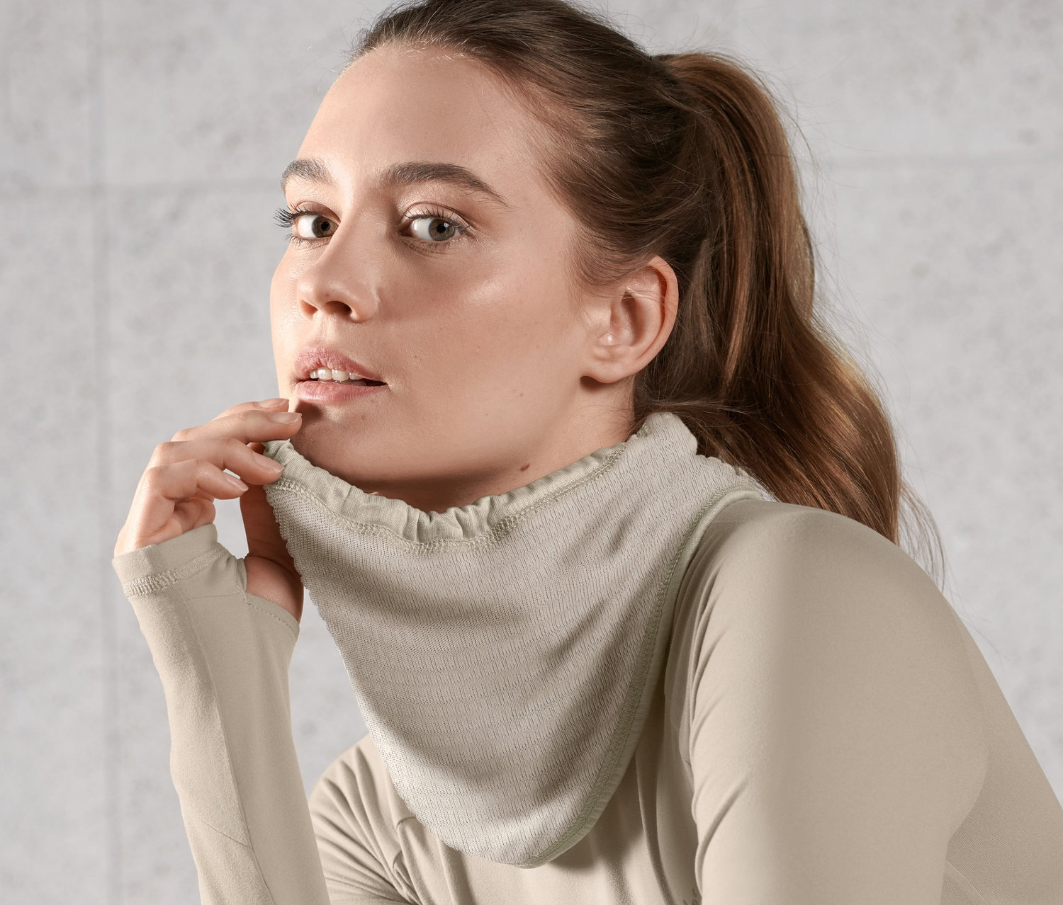 Femme portant un foulard thermique multifonction marron clair et un haut à manches longues.