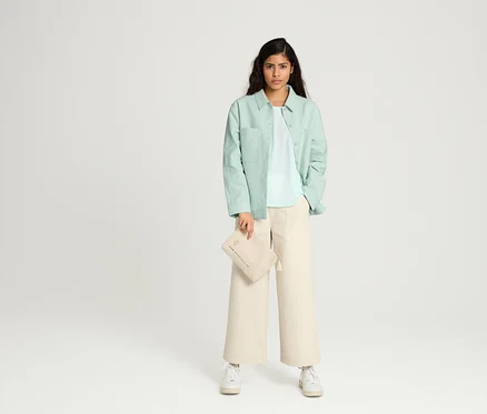 Femme posant en jupe-culotte NAH/STUDIO en coton non coloré et veste chemisier NAH/STUDIO en coton recyclé.