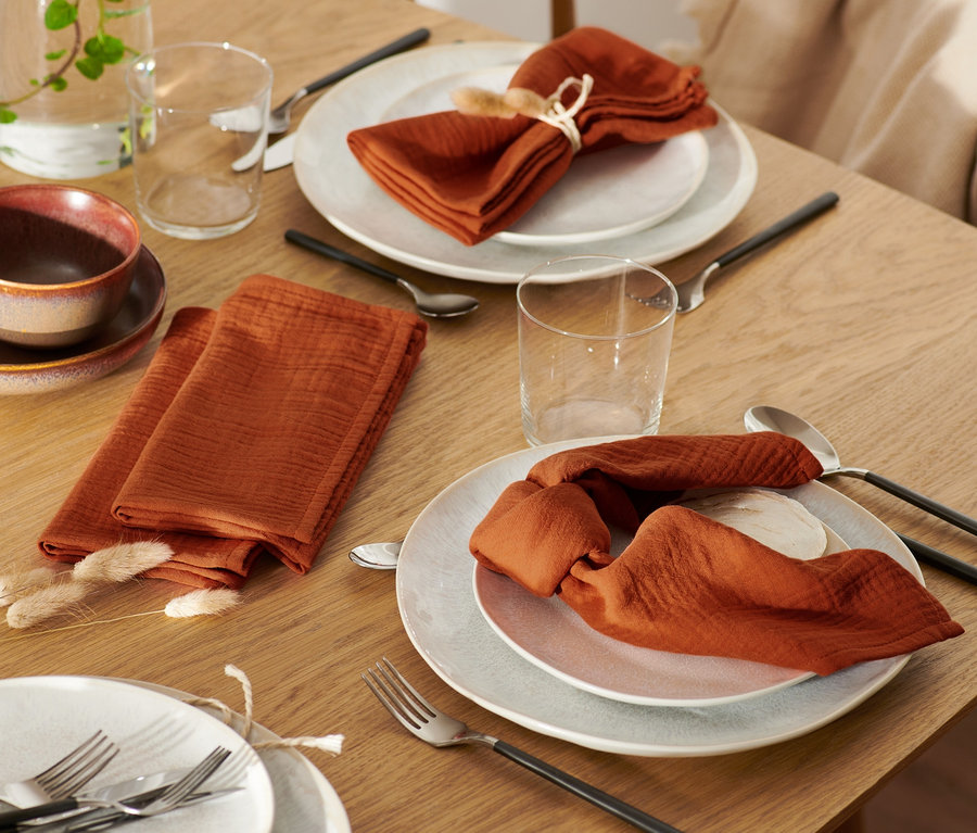 Des serviettes en mousseline sont posées sur la table.