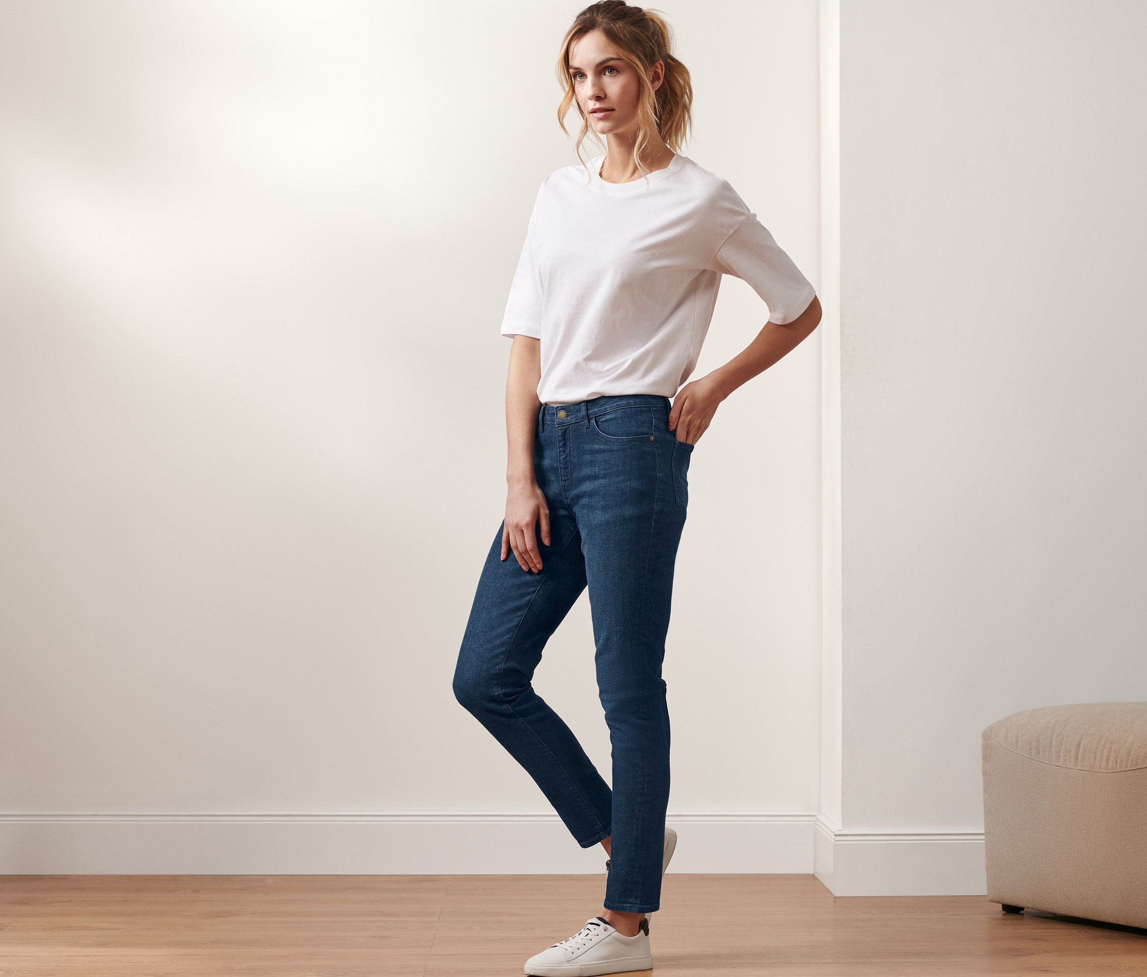 Femme posant en jean slim en denim « Fit Emma », denim bleu foncé et t-shirt blanc.