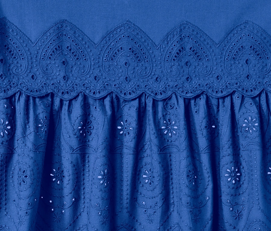 Détail d'un chemisier long bleu à broderie.