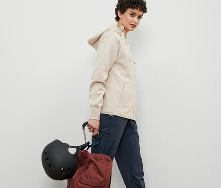 Femme marchant et portant un casque et un sac à dos attachés par 2 mousquetons XXL.