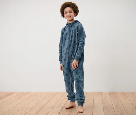 Un garçon debout porte une combinaison d’intérieur pour enfant avec des étoiles.