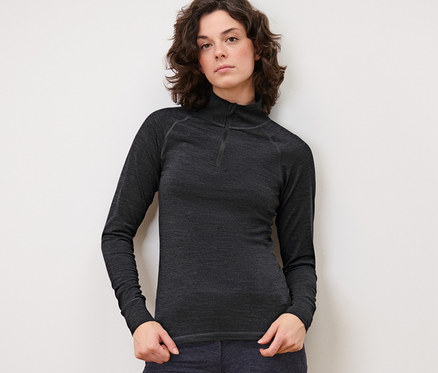 Femme posant en T-shirt technique avec laine certifiée RWS anthracite et pantalon foncé.