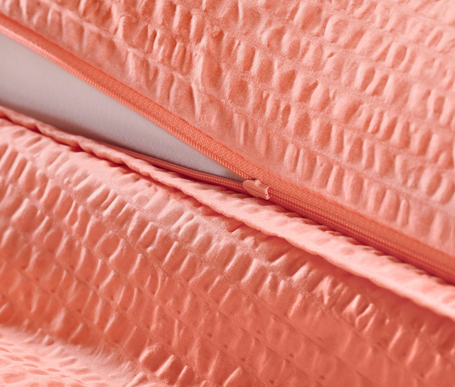 Gros plan d'une parure de lit en seersucker corail avec fermeture éclair.