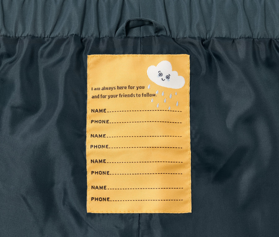 Intérieur du pantalon imperméable pour tout-petit avec une étiquette jaune avec des lignes pour le nom et le téléphone.