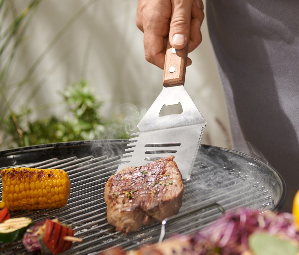 Un homme fait griller un steak avec un outil polyvalent pour barbecue.
