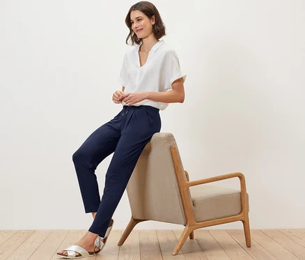 Une femme est assise sur une chaise et porte un pantalon en jersey bleu foncé.