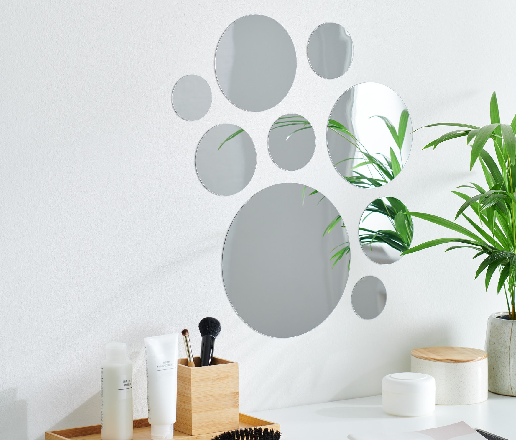 Neuf autocollants miroir sont disposés en cercle sur un mur blanc au-dessus d'une table blanche.