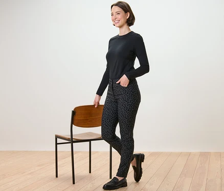 Femme posant à côté d'une chaise portant un pantalon imprimé en bengaline.