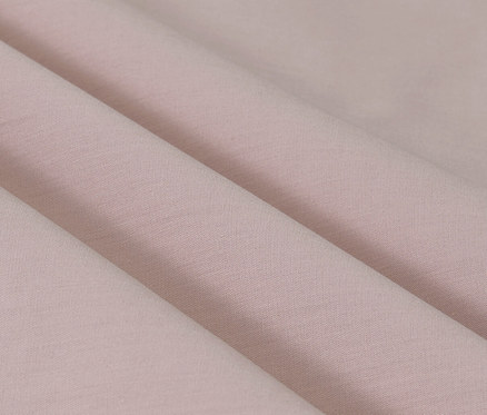 Gros plan sur les plis d'une parure de lit en percale rose de taille standard et grande taille.