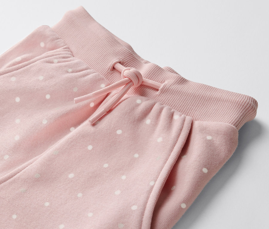 Détail de 2 pantalons de survêtement à pois pour bébé.