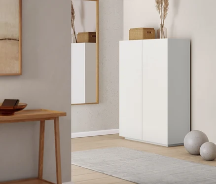 Un miroir mural et un meuble haut dans un intérieur. Une console avec 2 étagères est visible à gauche.