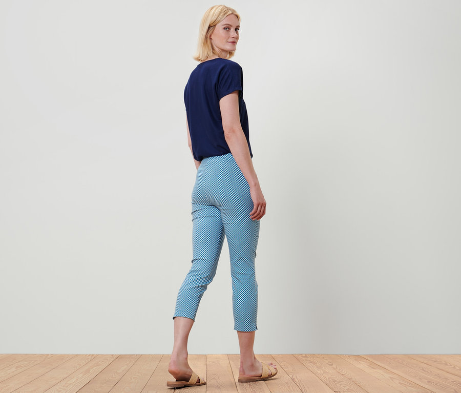 Femme regardant par-dessus son épaule portant un t-shirt bleu et un pantalon stretch 7/8 imprimé intégral.