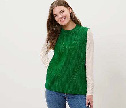 Femme portant un pull sans manches en maille vert.
