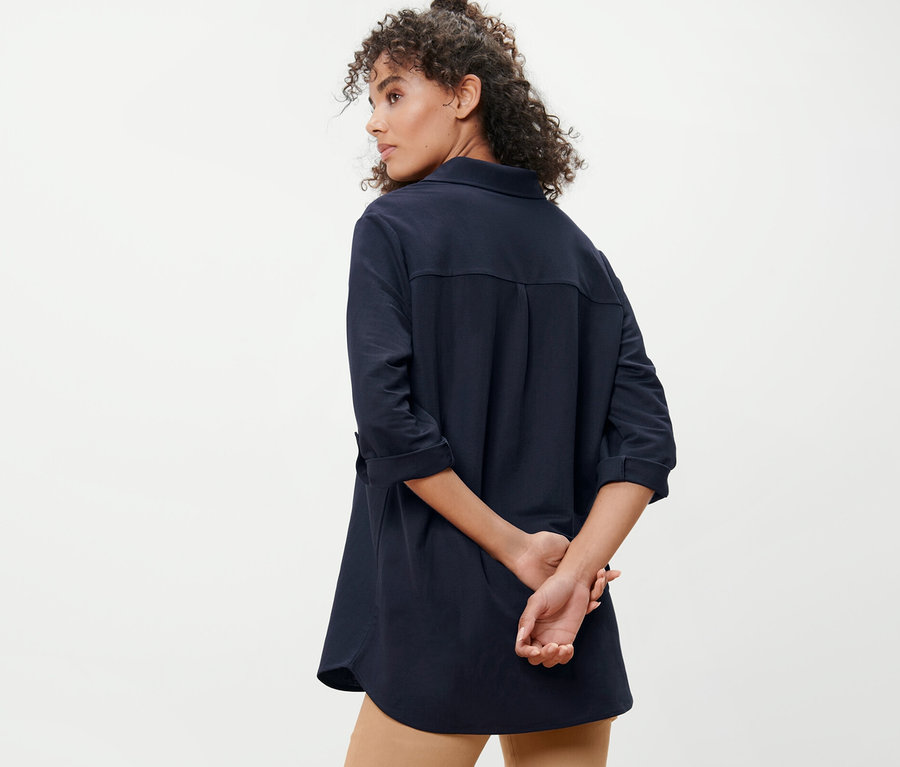 Femme posant de dos et portant un chemisier en jersey piqué bleu foncé.