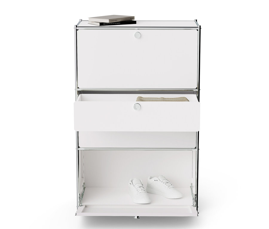 Commode en métal blanche « CN3 » avec 2 abattants, 2 tiroirs, un livre sur le dessus et des chaussures en bas.