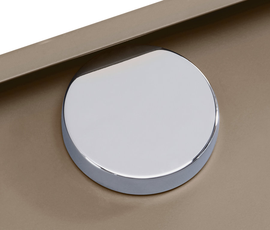 Détail d'un bouton chromé brillant sur une surface beige.