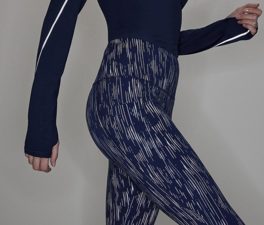 Vue partielle d'une femme portant un haut à manches longues bleu marine et un legging à motifs.
