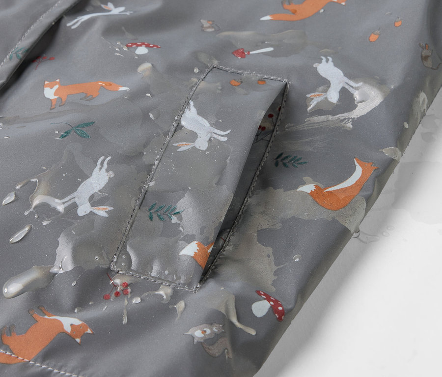 Détail d'une veste de pluie thermique pour enfant avec des renards, des lièvres et des champignons.