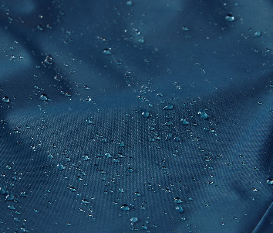 Gros plan sur un pantalon de pluie thermique pour enfant avec des gouttes d'eau à la surface.
