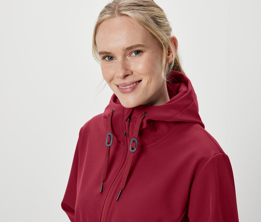 Portrait d'une femme souriante portant un sweat à capuche bordeaux.