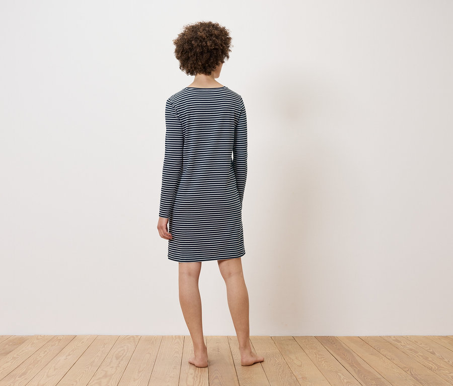 Une femme, vue de dos, porte une robe rayée.