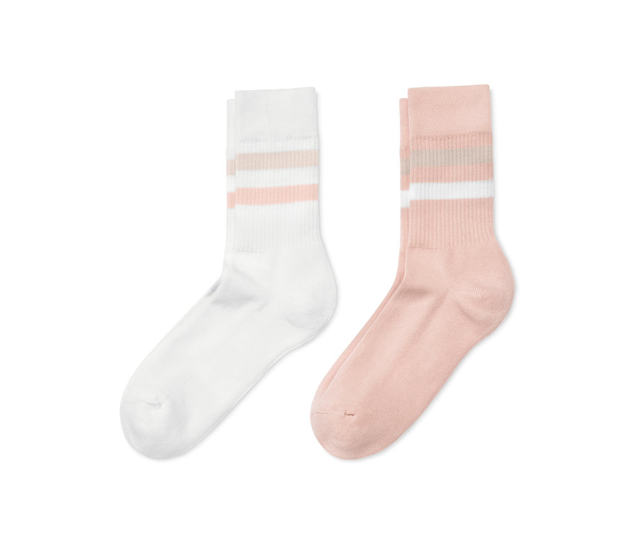 Deux paires de chaussettes côtelées, une paire rose avec des rayures blanches sur le dessus, une paire blanche avec des rayures roses sur le dessus.