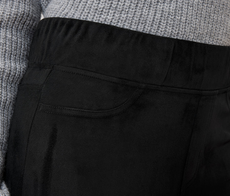 Détail d'un pantalon noir pour femme avec une poche et un pull gris.