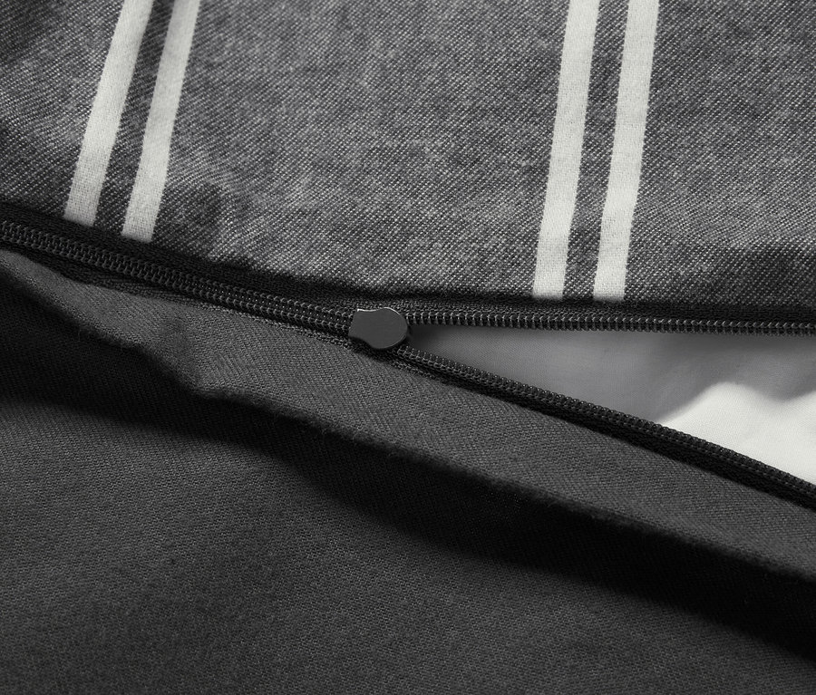 Détail d'une housse de couette grise à rayures blanches avec une fermeture éclair noire.