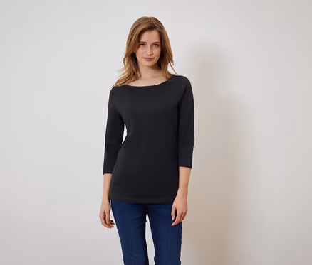 Une femme porte un t-shirt noir à manches trois-quarts et un jean bleu.