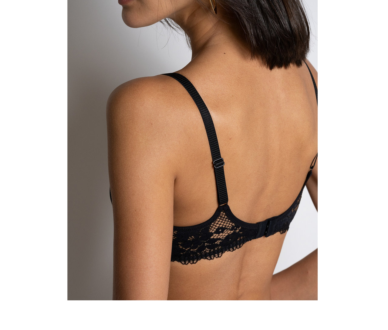Femme vue de dos, portant un soutien-gorge « Nina » Passionata noir en dentelle avec des bretelles réglables.