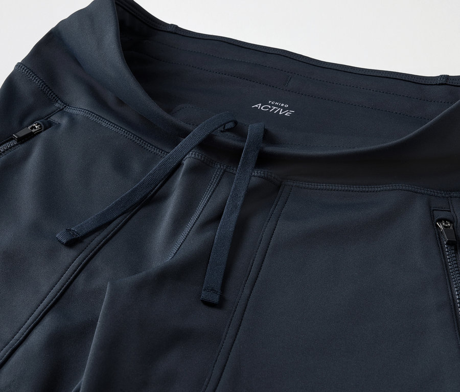 Gros plan d'un pantalon de survêtement bleu foncé avec poches zippées et cordon de serrage.