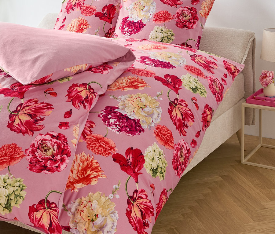 Linge de lit rose à motif floral sur un lit.